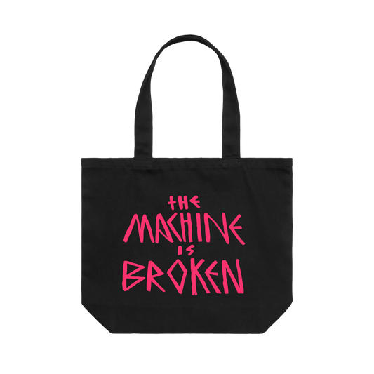Black tote bag featuring pink text reading "the machine is broken" printed on one side and an Arcade Fire elephant print on the other.
